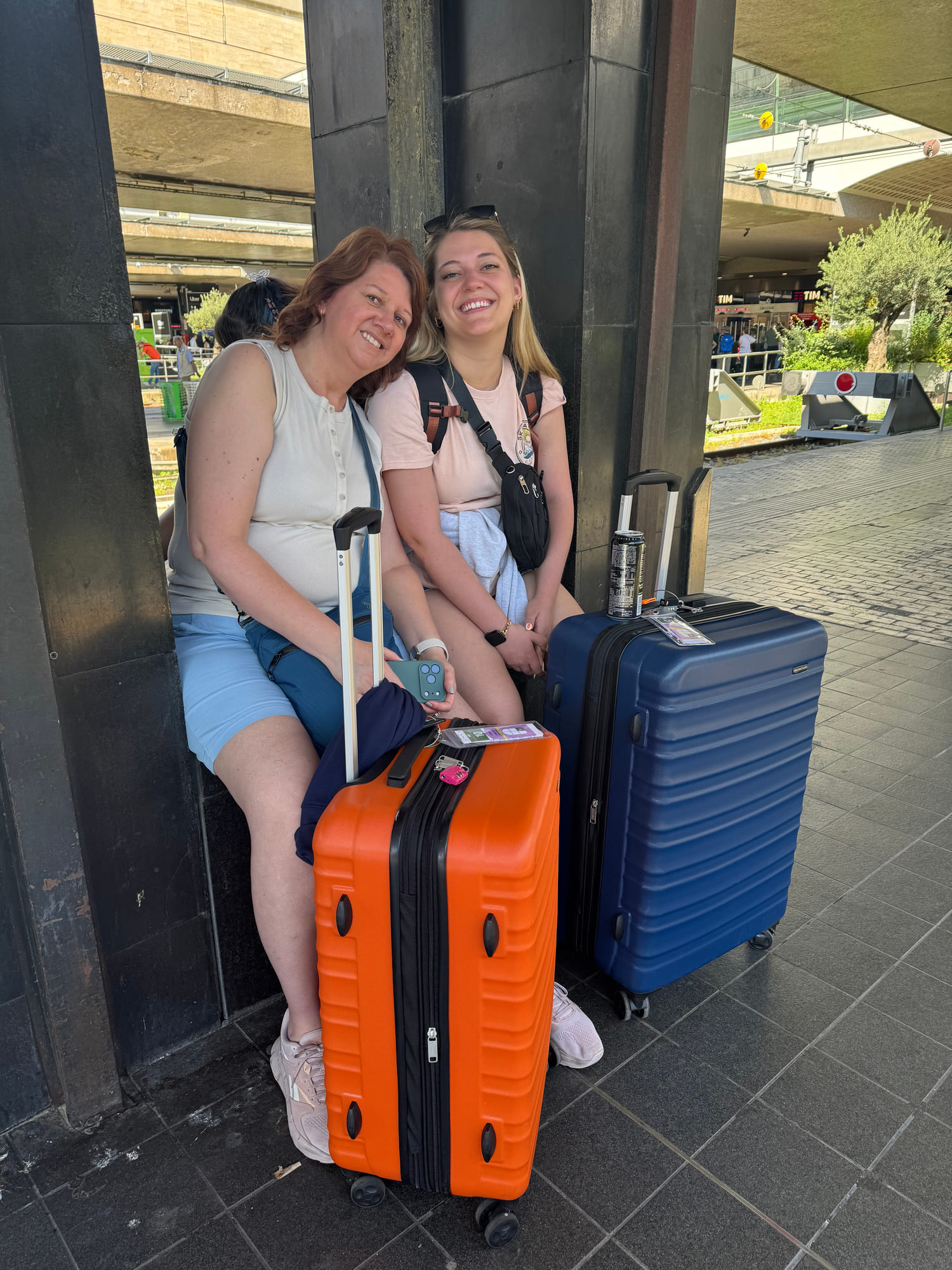Angela and a family member waiting with several suitcases beside the train platforms in Rome