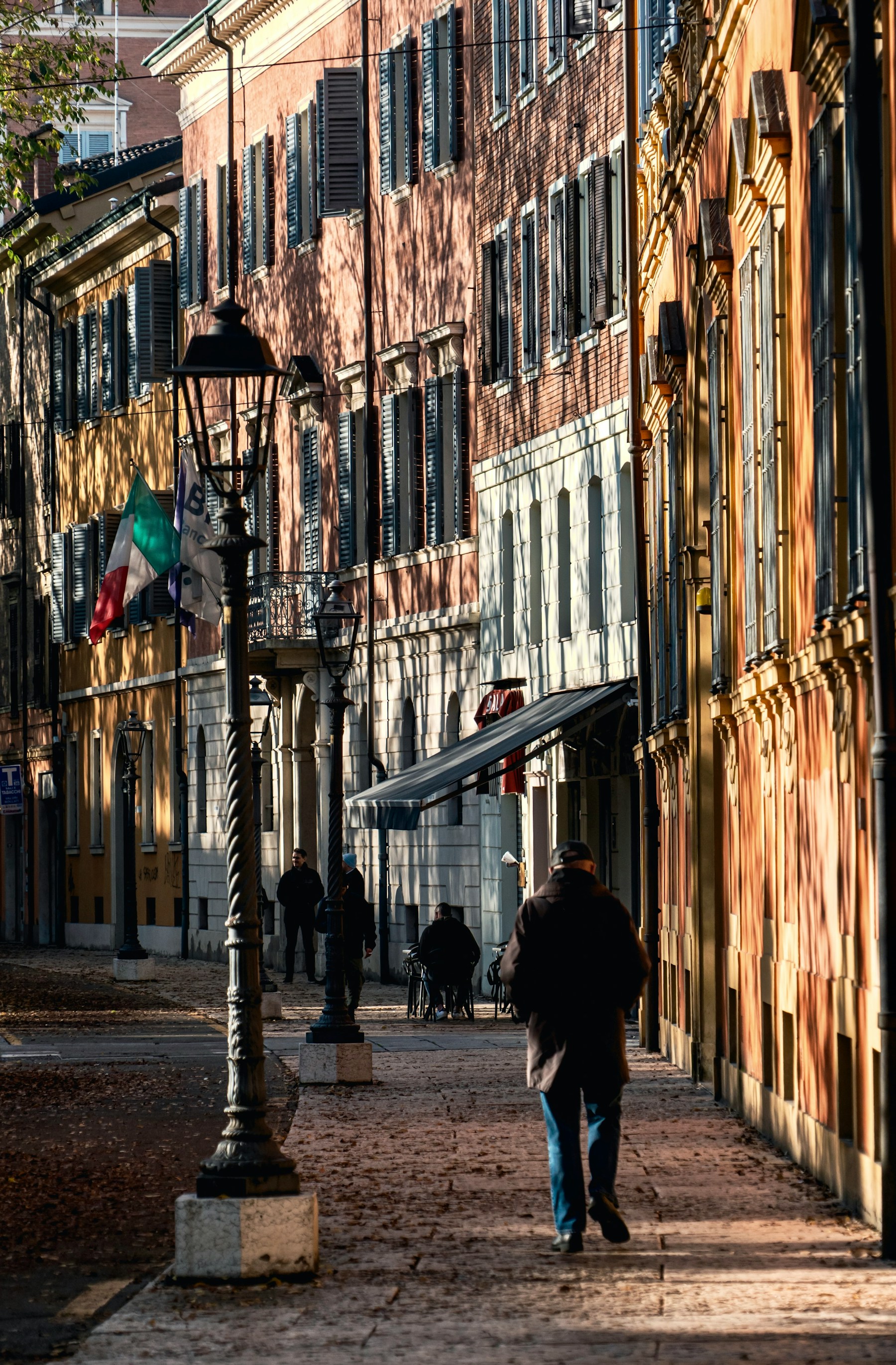 A traveler walking down a quiet sunlit street in Modena