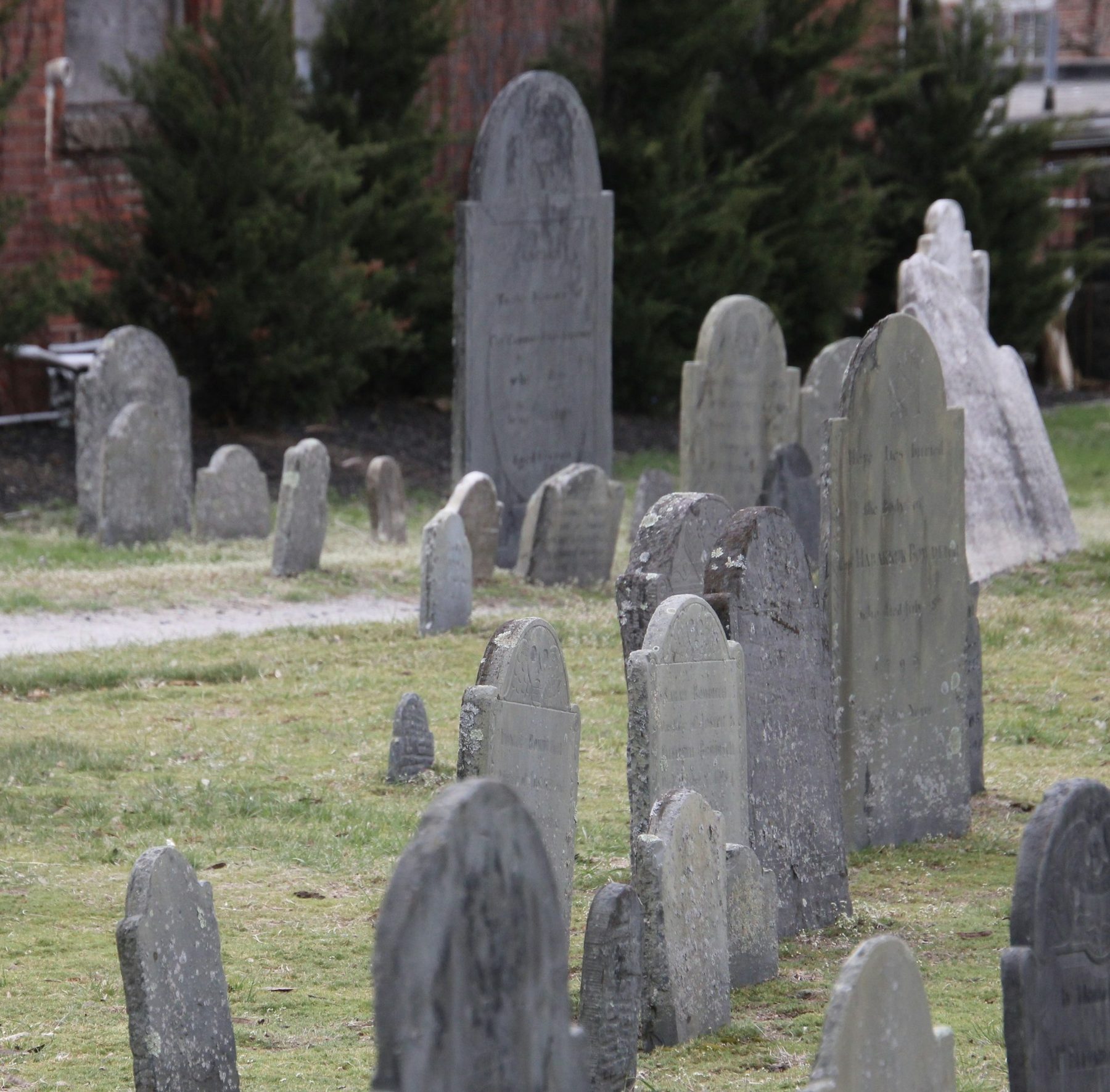 Historic gravestones beneath trees at Old Burying Point Cemetery in Salem, Massachusetts