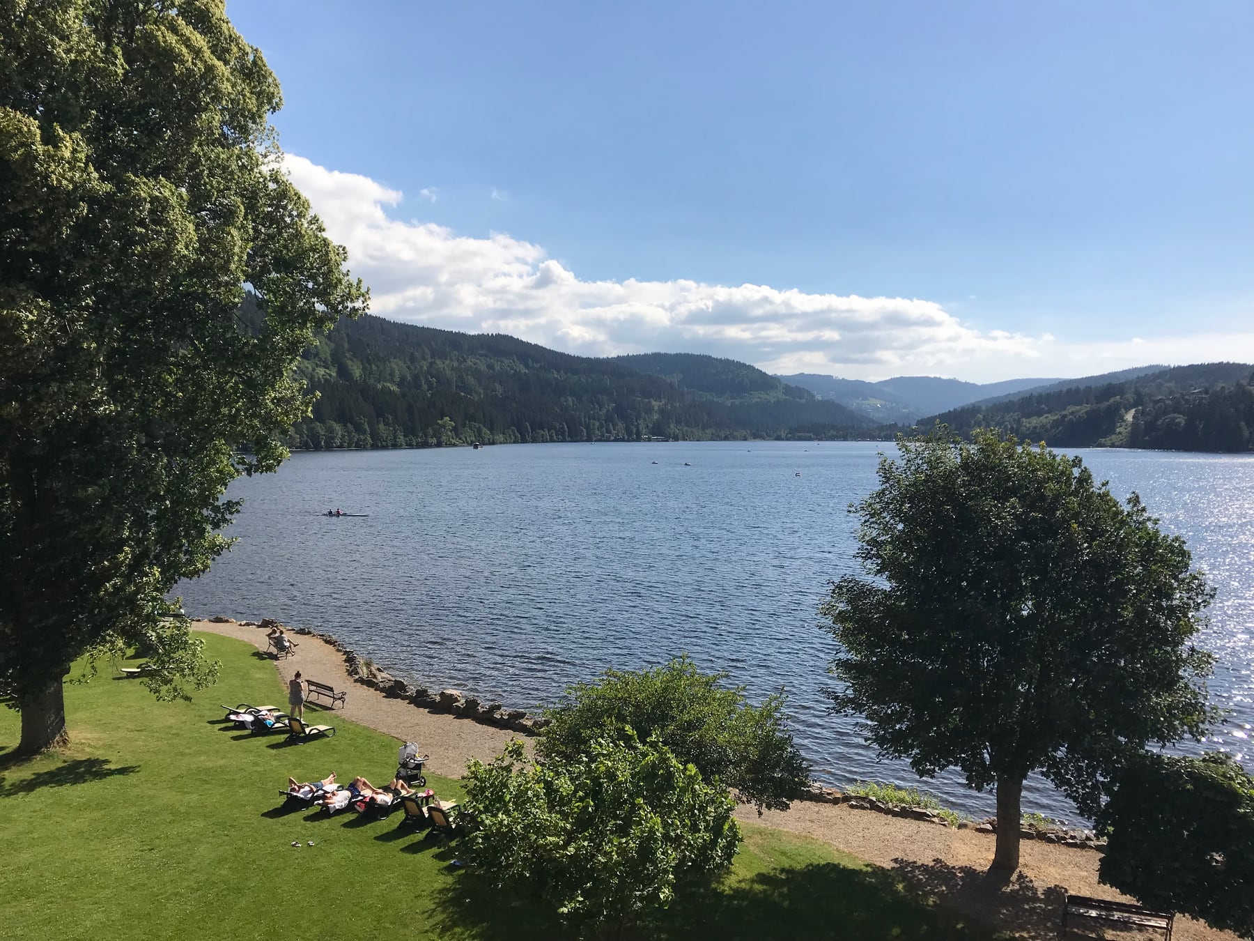 Lake Titisee surrounded by green hills beneath a blue summer sky