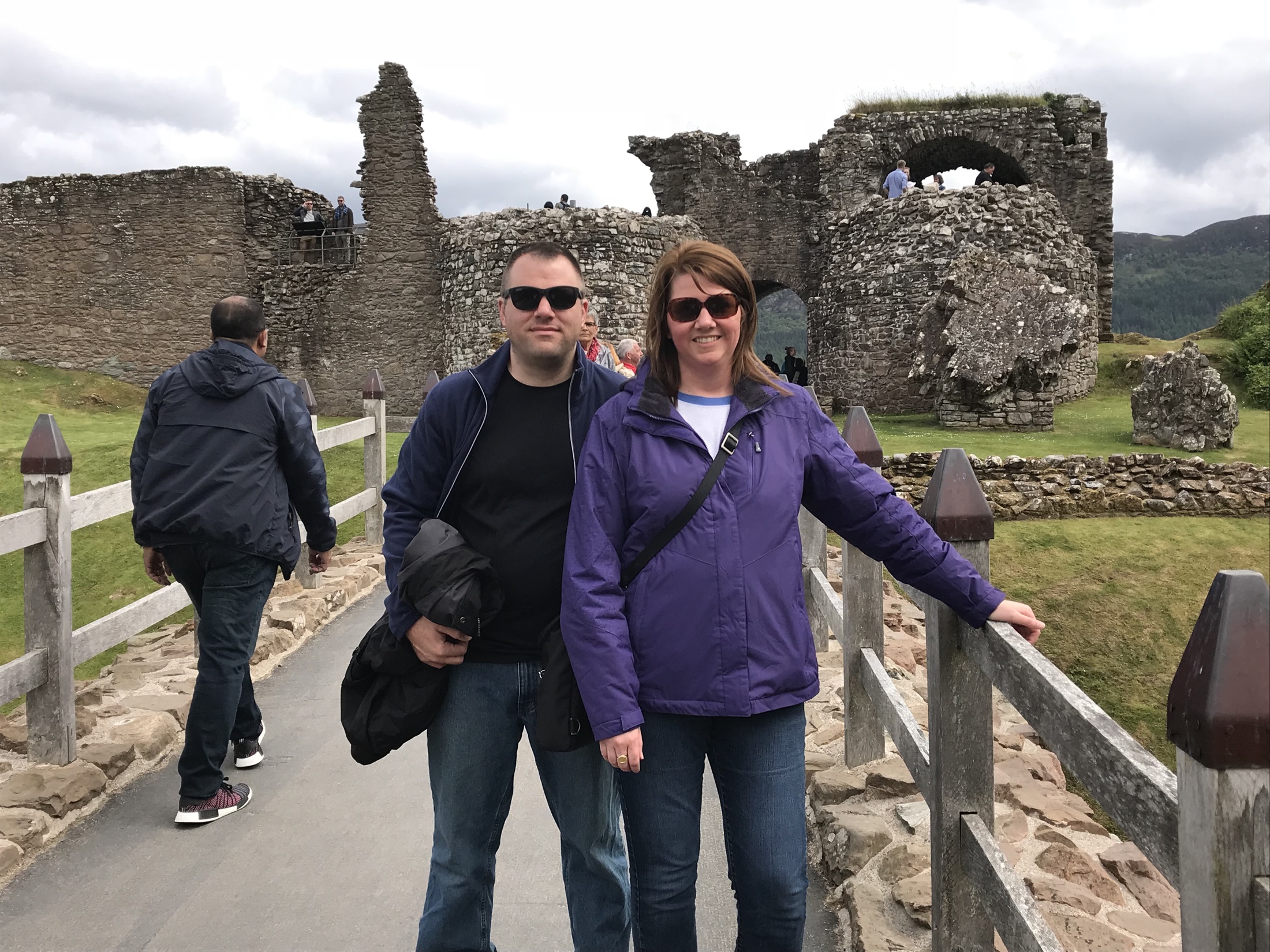 Angela and Brian standing together on a wooden bridge inside Urquhart Castle