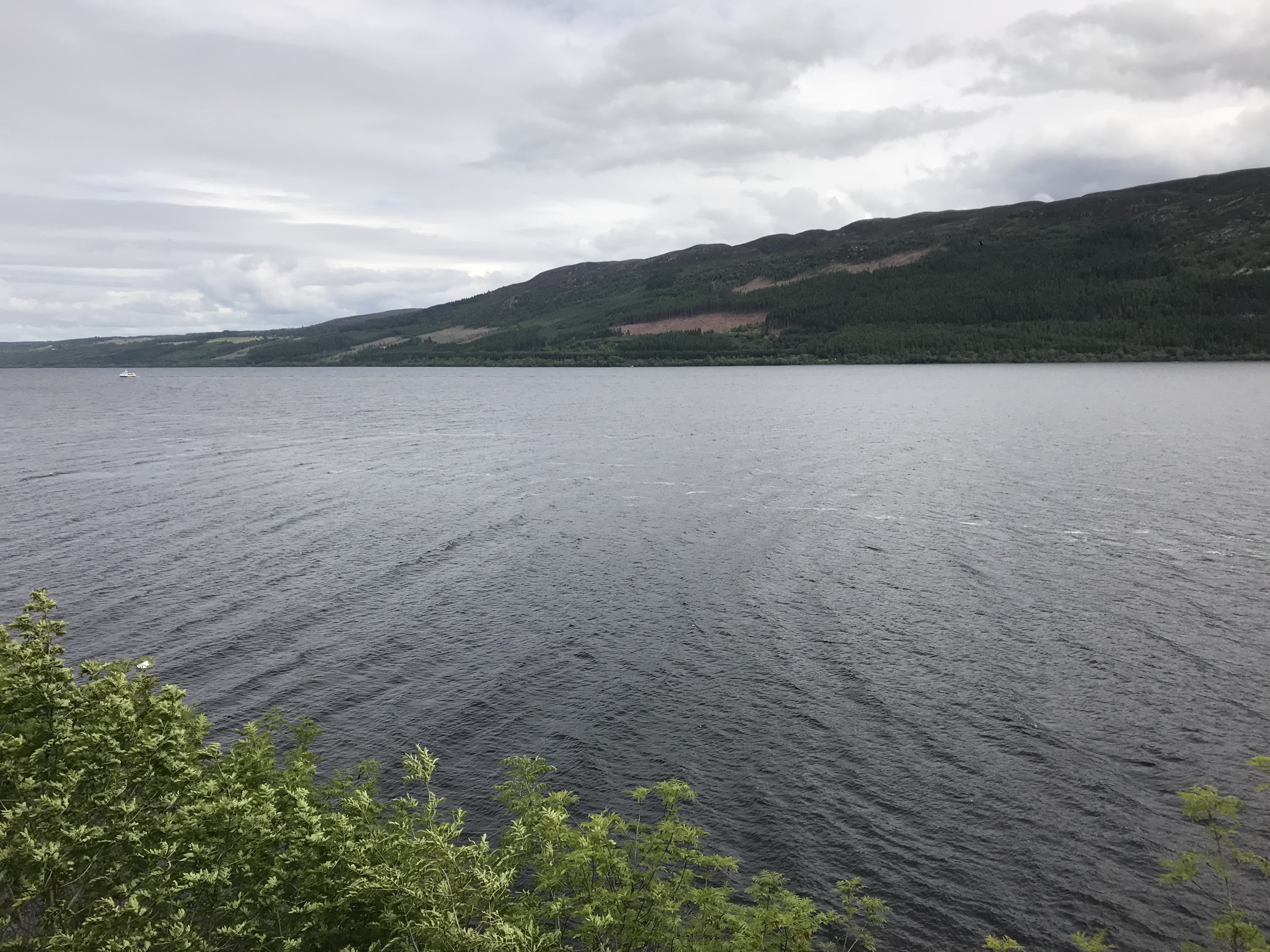 A wide view across the dark water and wooded hills of Loch Ness from Urquhart Castle