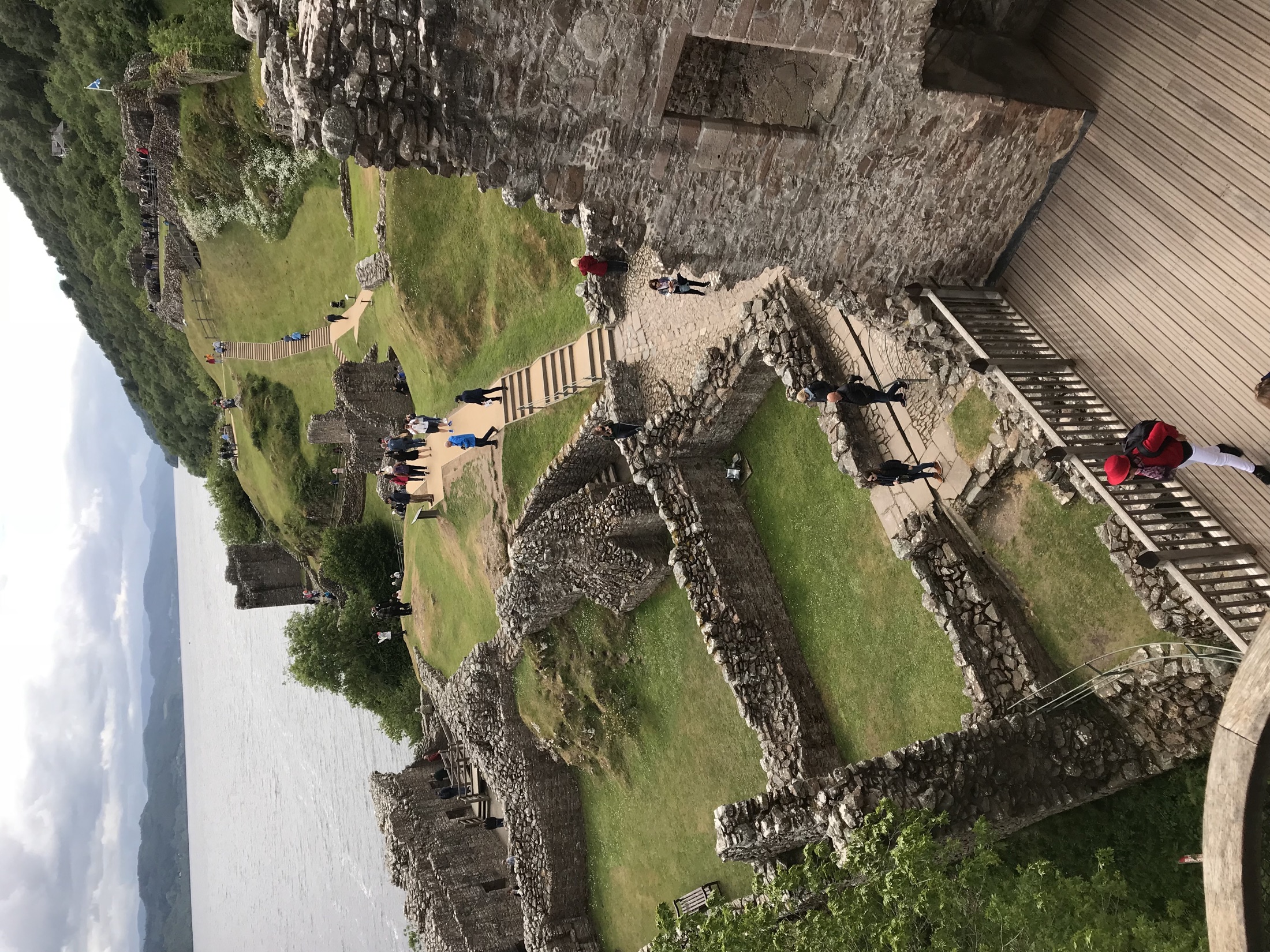 The walls, paths, and grassy enclosures of Urquhart Castle seen from above