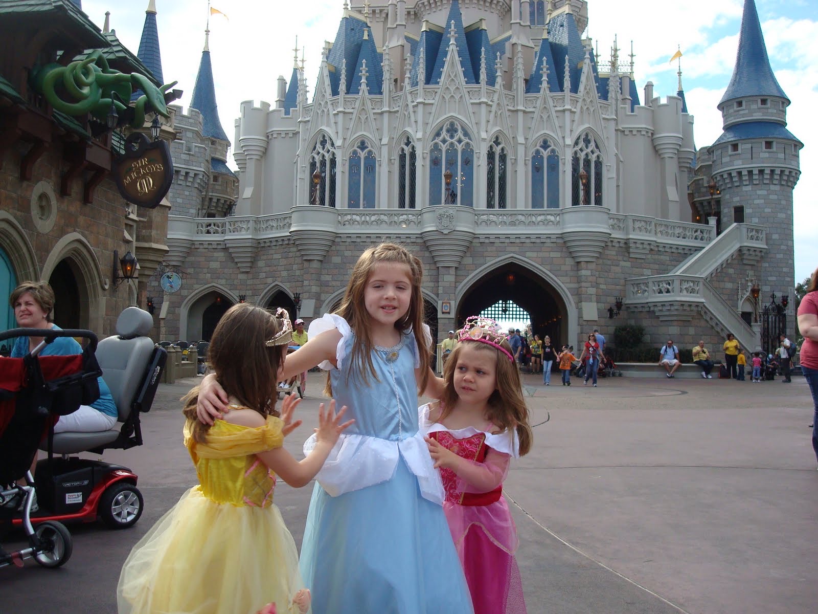 Angela’s three young daughters dressed as princesses in front of Cinderella Castle