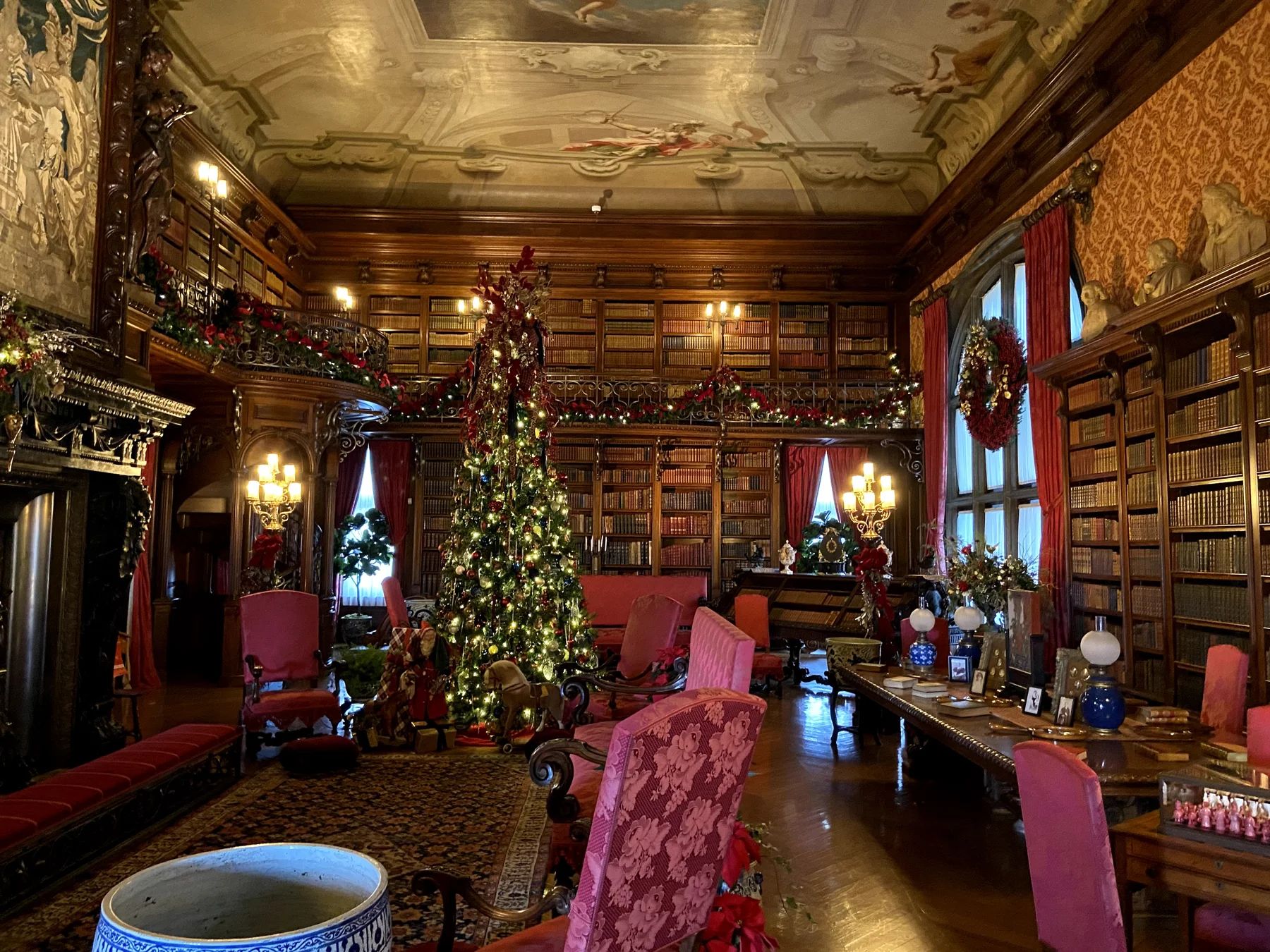 Biltmore’s library with bookshelves, a painted ceiling, and a decorated Christmas tree