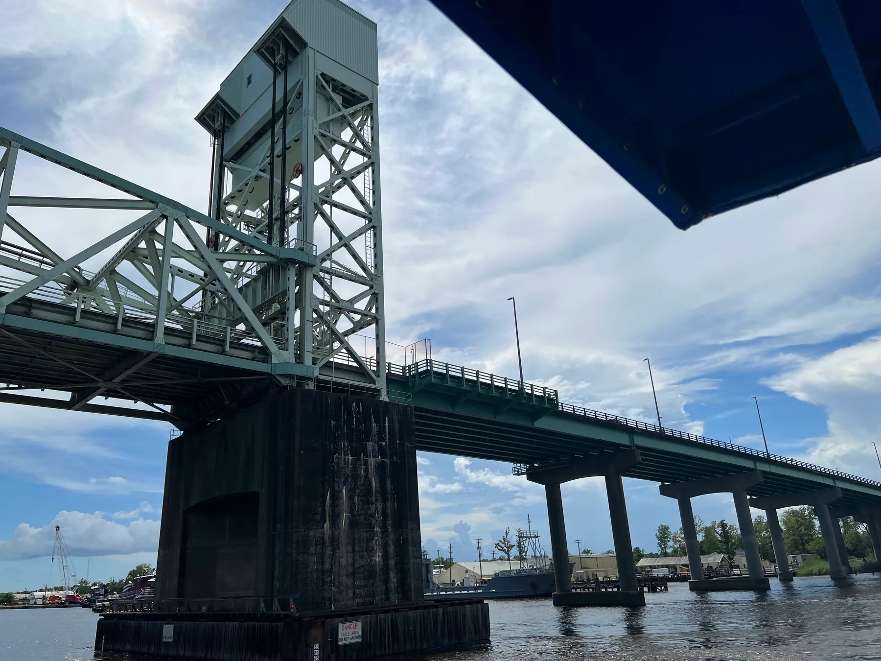 The vertical-lift Cape Fear Memorial Bridge viewed from beneath a boat canopy on the Cape Fear River