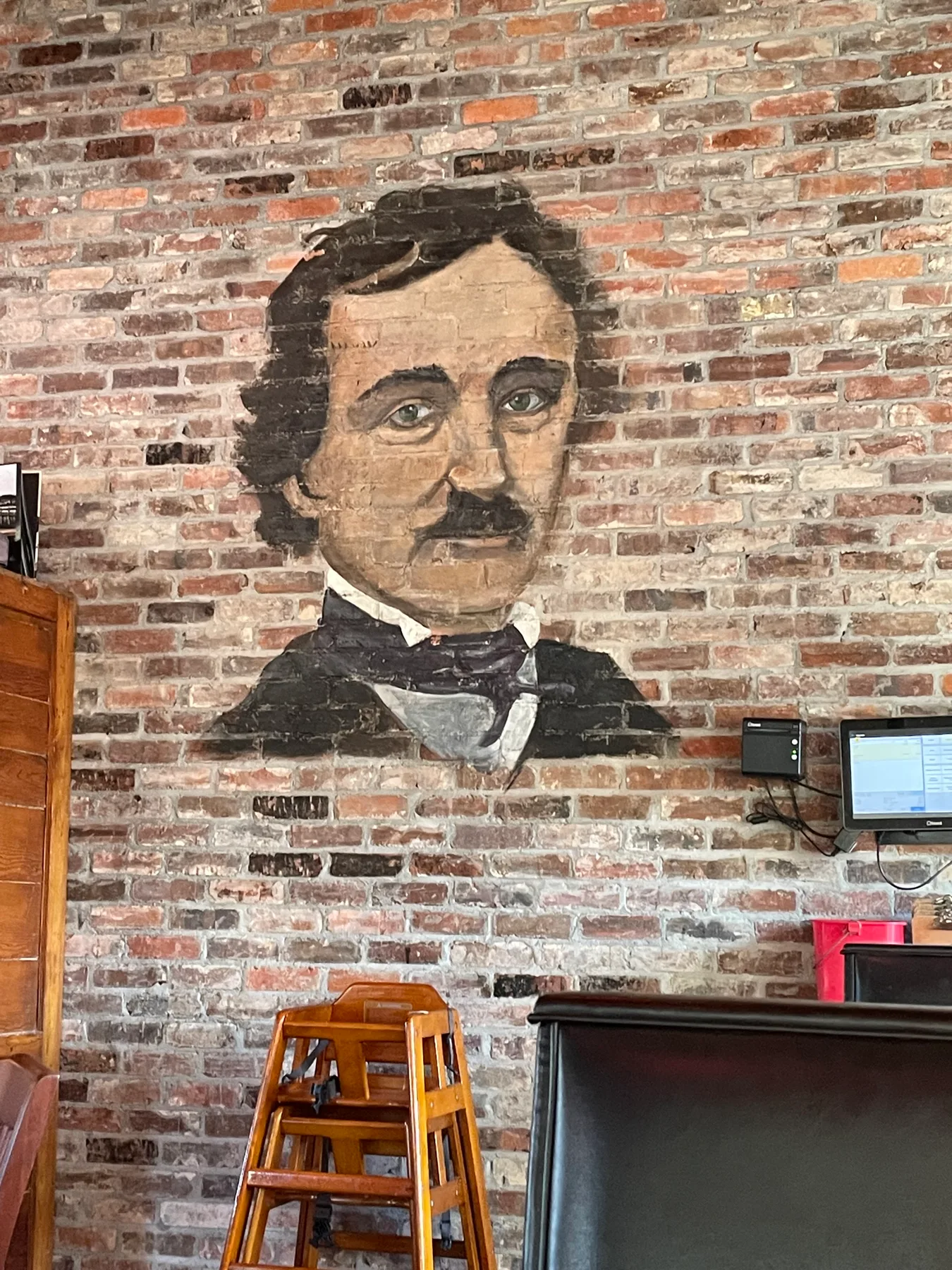A painted portrait of Edgar Allan Poe on the brick wall inside Poe’s Tavern at Wrightsville Beach