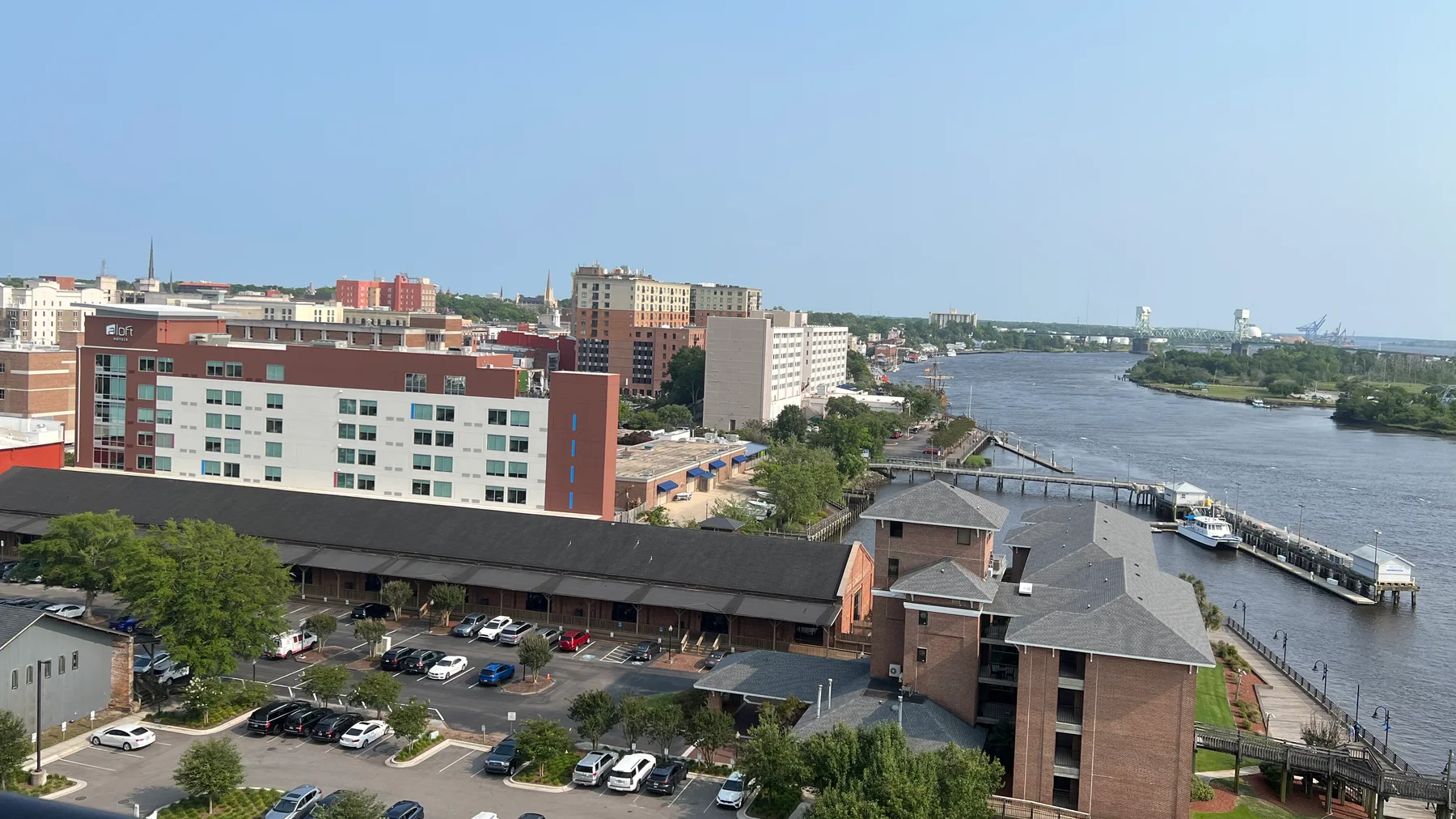 Elevated view across downtown Wilmington, the Riverwalk, Cape Fear River, docks, and Cape Fear Memorial Bridge